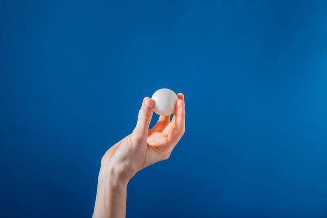 hand-holding-ping-pong-ball-on-blue-background.jpg
